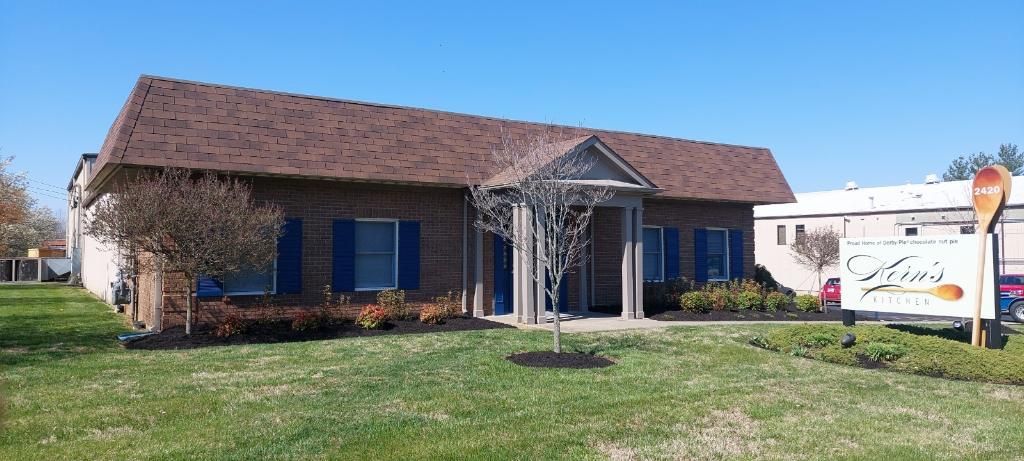 A brick building with a brown roof, blue shutters, and a sign that says 