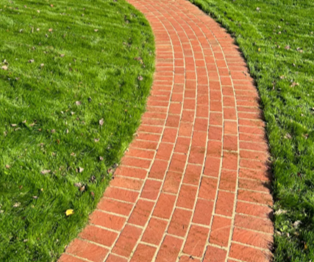 Curved red brick path winding through green grass in a park Curved red brick path winding through green grass in a park