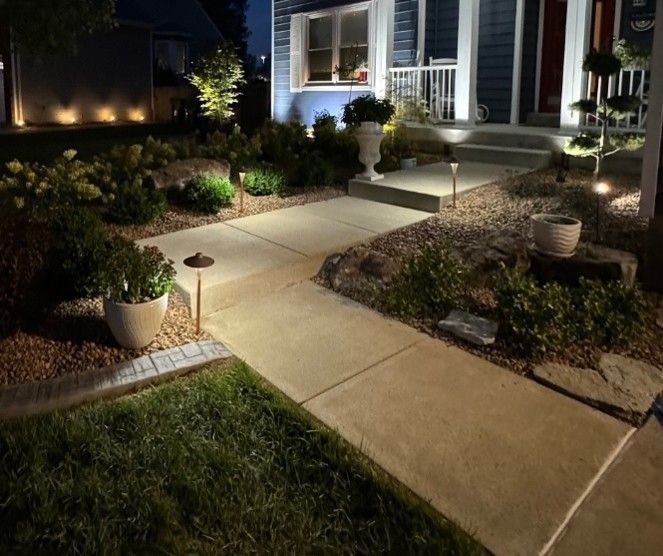 Professionally installed outdoor landscape lighting illuminating a concrete sidewalk, garden beds, shrubs, and front porch steps of a Mount Washington, KY home at night, showcasing seasonal curb appeal and low-voltage path lighting Professionally installed outdoor landscape lighting illuminating a concrete sidewalk, garden beds, shrubs, and front porch steps of a Mount Washington, KY home at night, showcasing seasonal curb appeal and low-voltage path lighting