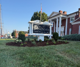 Parsons Funeral Home sign in front of a red brick building with landscaped grass and shrubs Parsons Funeral Home sign in front of a red brick building with landscaped grass and shrubs