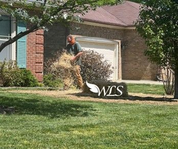 Man mulching a front yard with a house in the background.