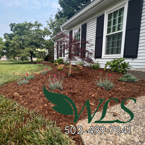 Landscaped home exterior with a new mulch bed, flowering plants, and a small tree. The business logo and phone number are at the bottom.