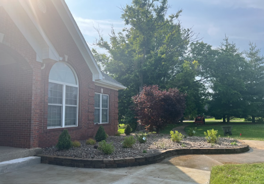 Manicured shrub beds and stone retaining wall from commercial landscape service.