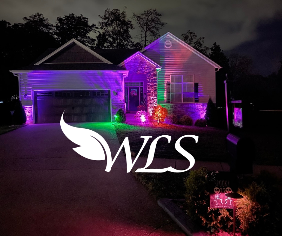 House exterior illuminated with pink, purple, and green lights at night. The company logo