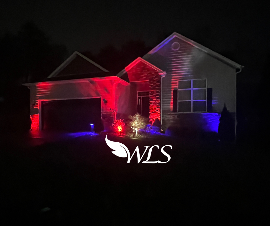 A house at night illuminated with red and blue lights. The garage and front are lit.