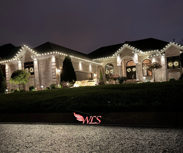 A house lit up with white Christmas lights along the roofline and on the bushes in front. A house lit up with white Christmas lights along the roofline and on the bushes in front.