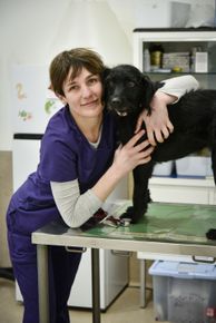 una donna è in piedi accanto a un cane nero su un tavolo.