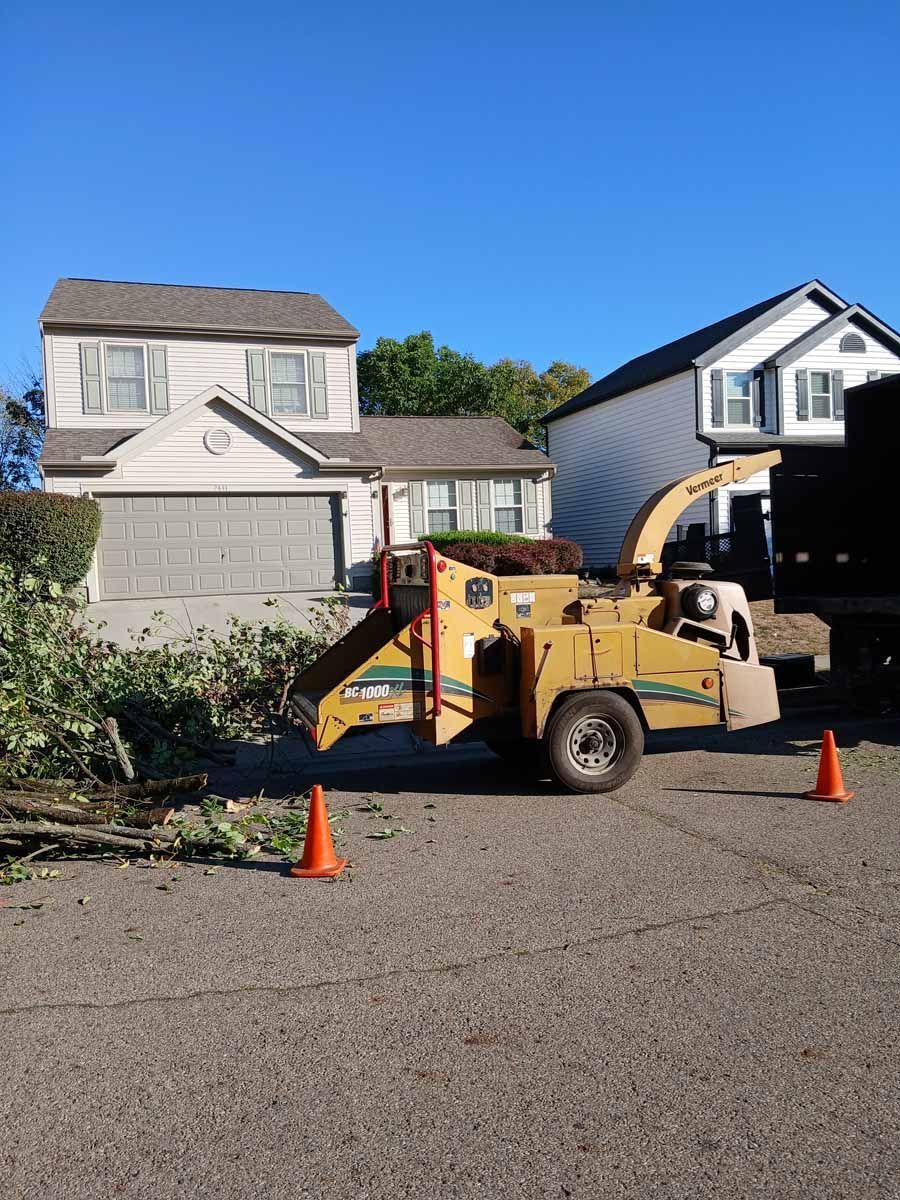 A tree chipper is parked in front of a house.