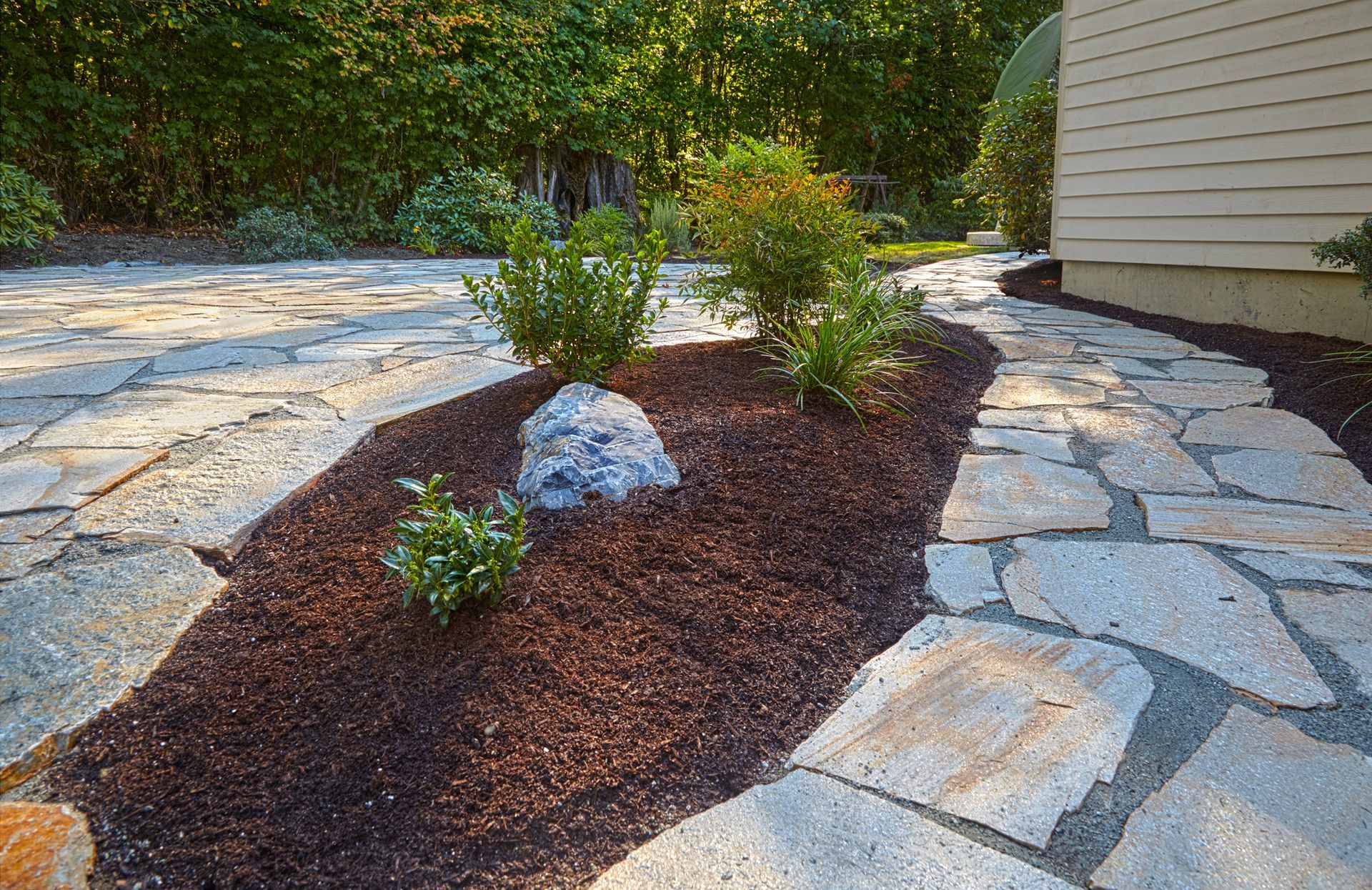 A stone walkway leading to a house with a rock in the middle.