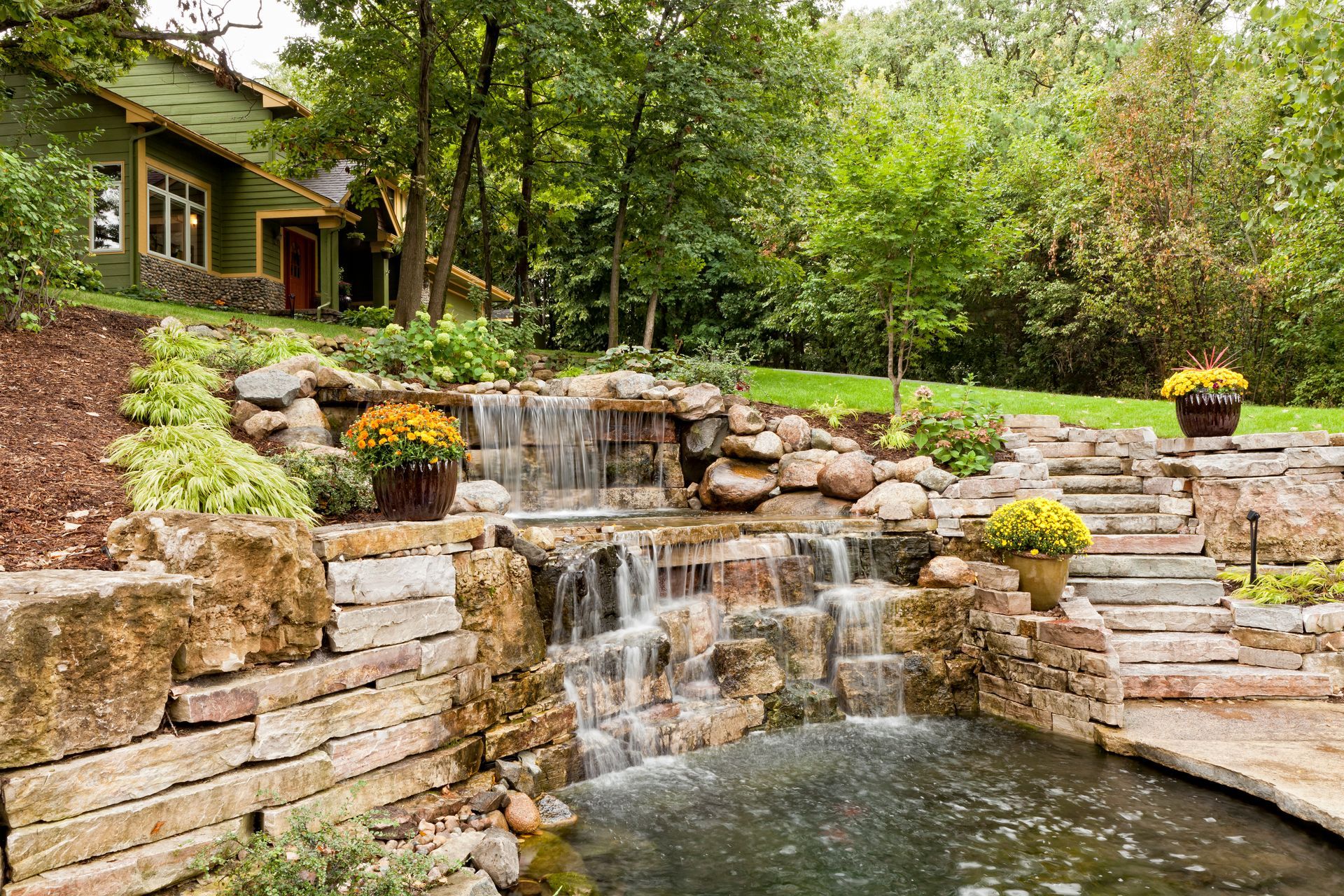 There is a waterfall in the backyard of a house.