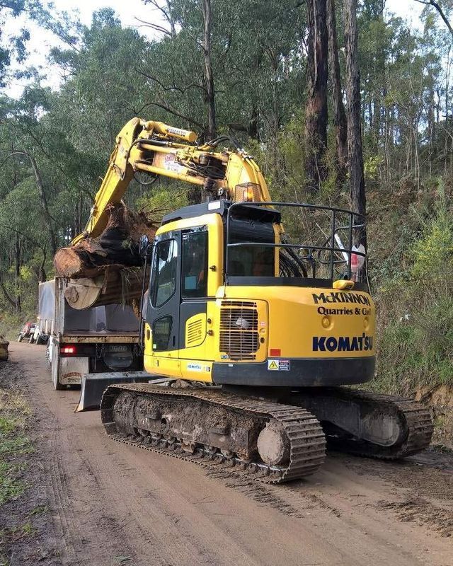 A Yellow And Black Komatsu Excavator Is Driving Down A Dirt Road – Warrnambool, VIC - McKinnon Quarries & Civil