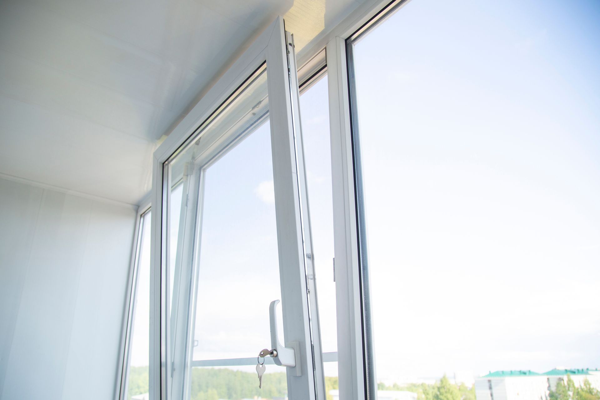 White casement window open, revealing a bright sky and trees.