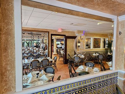 A restaurant with tables and chairs is seen through a window.
