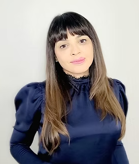A woman with long hair and bangs is wearing a blue top.