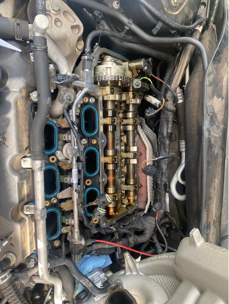 Car engine with intake manifold removed, exposing blue gasket openings and gold fuel rails in the engine bay