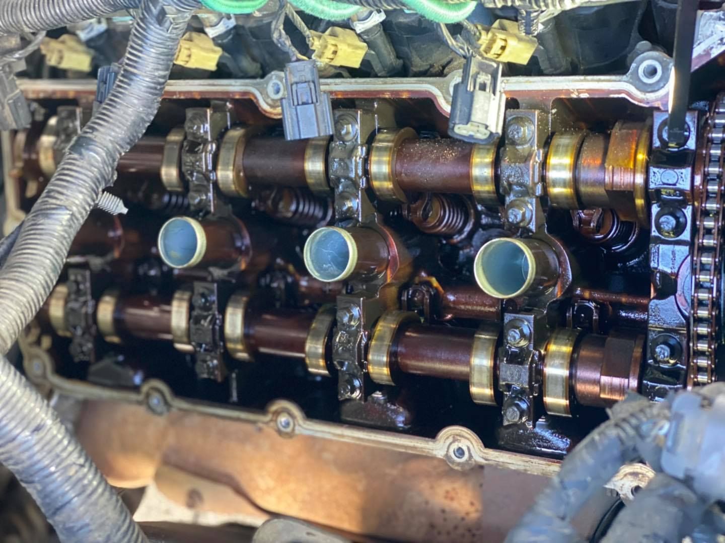 Engine top showing camshafts, covered in oil, with open valve covers.