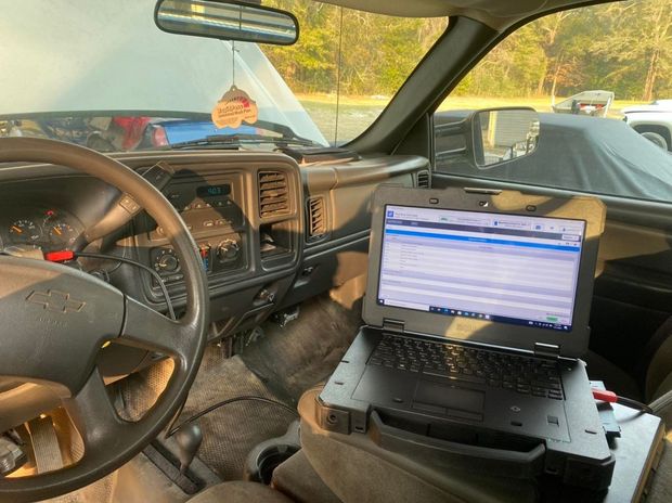 Interior of a truck with a laptop displaying diagnostic data. Hood is open.