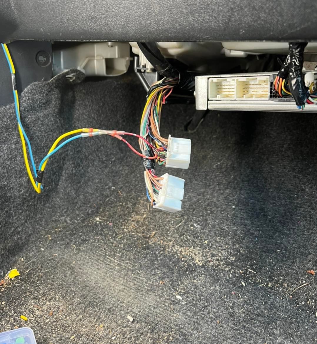 Exposed vehicle wiring: blue, yellow, and red wires connected to white connectors, inside a vehicle's interior.