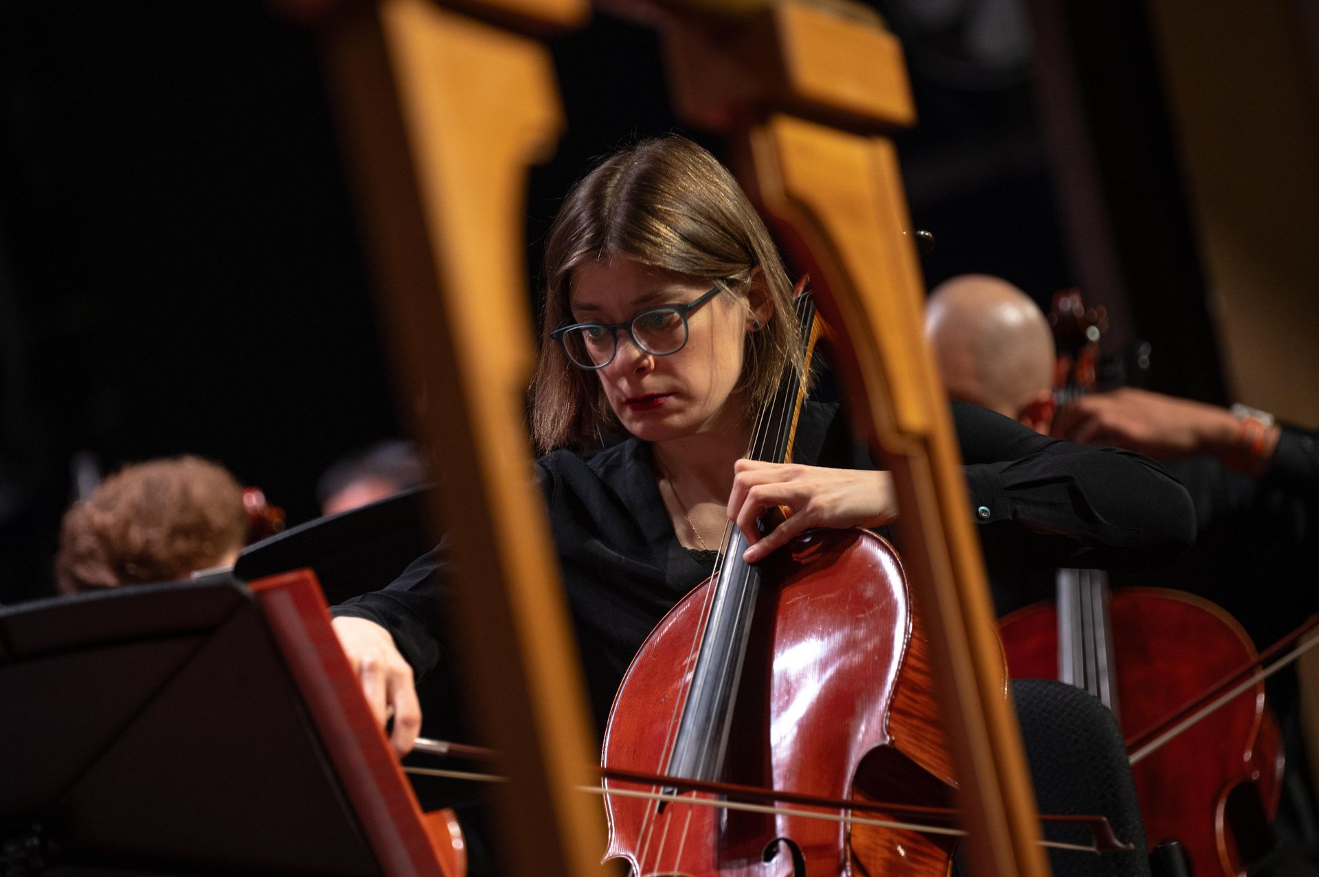 Cellist playing on stage in a concert hall, focused on the instrument.
