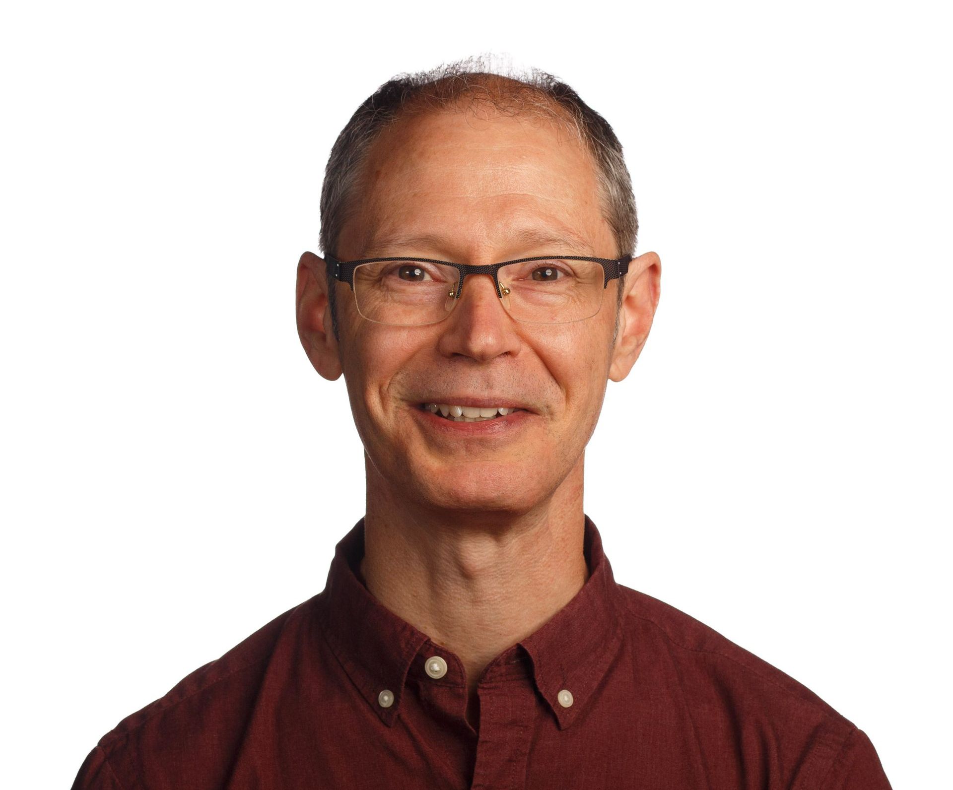 A man wearing glasses and a red shirt smiles for the camera.