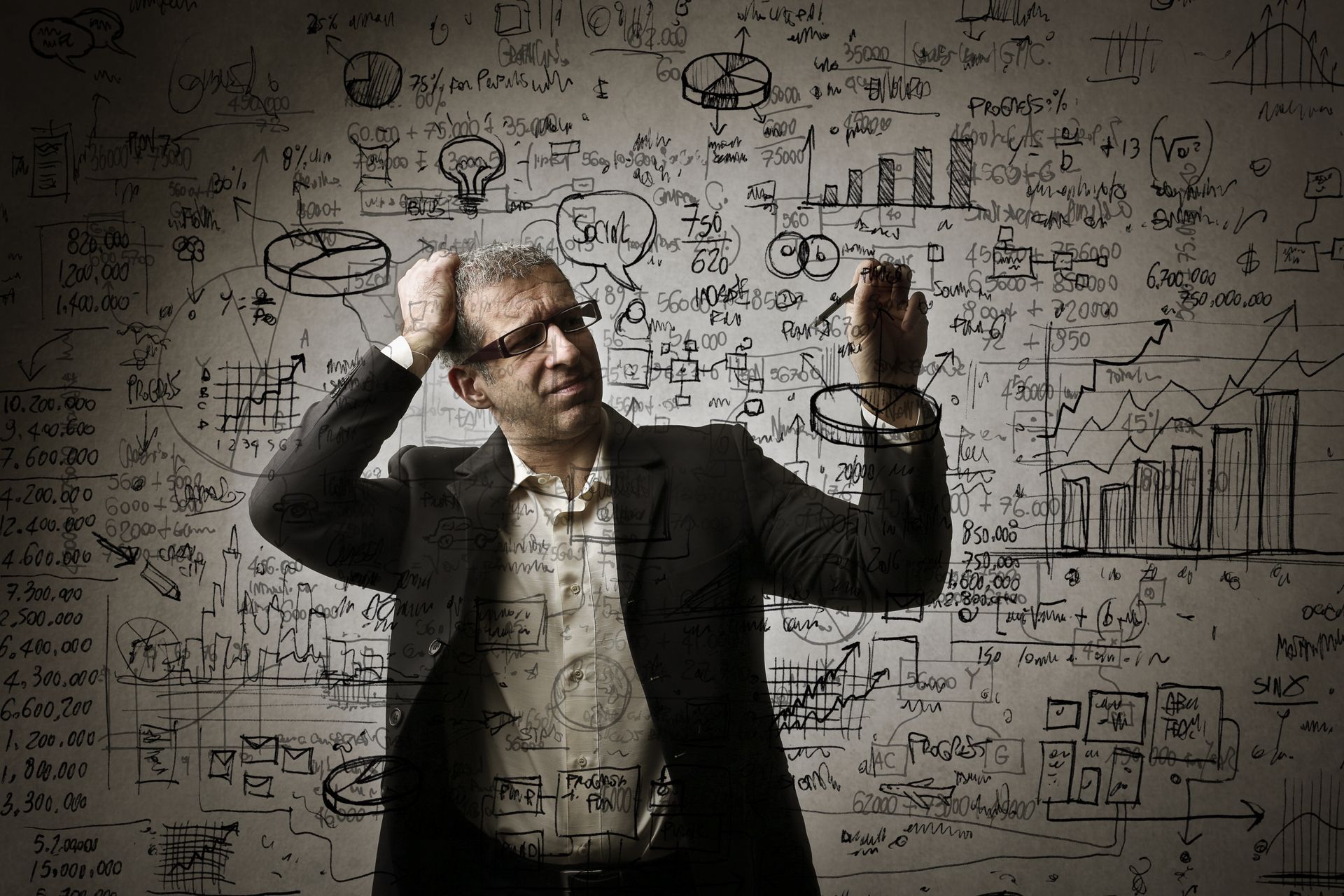 A man in a suit is standing in front of a wall with a lot of writing on it