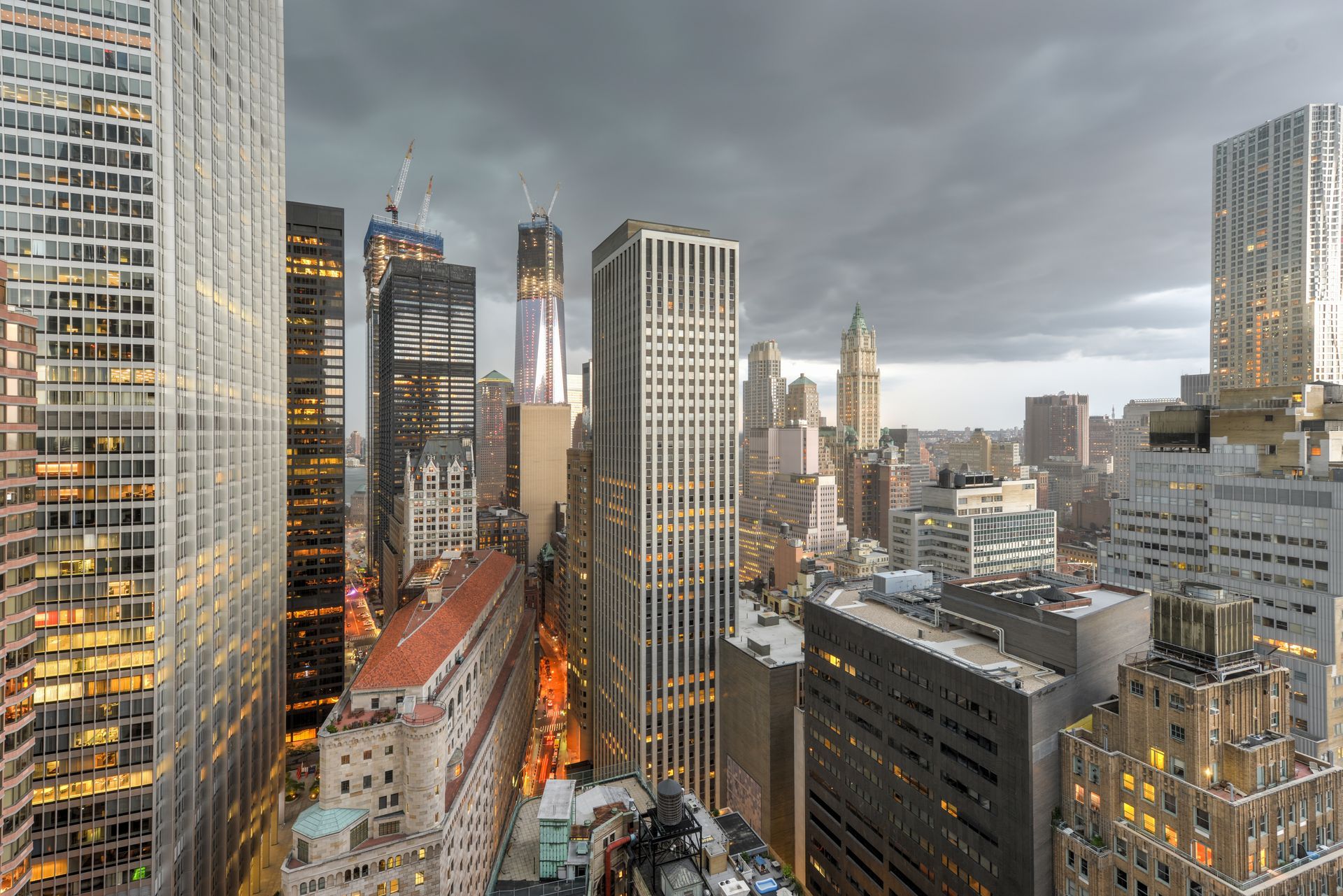 Downtown city skyline with tall glass skyscrapers under a cloudy sky at dusk