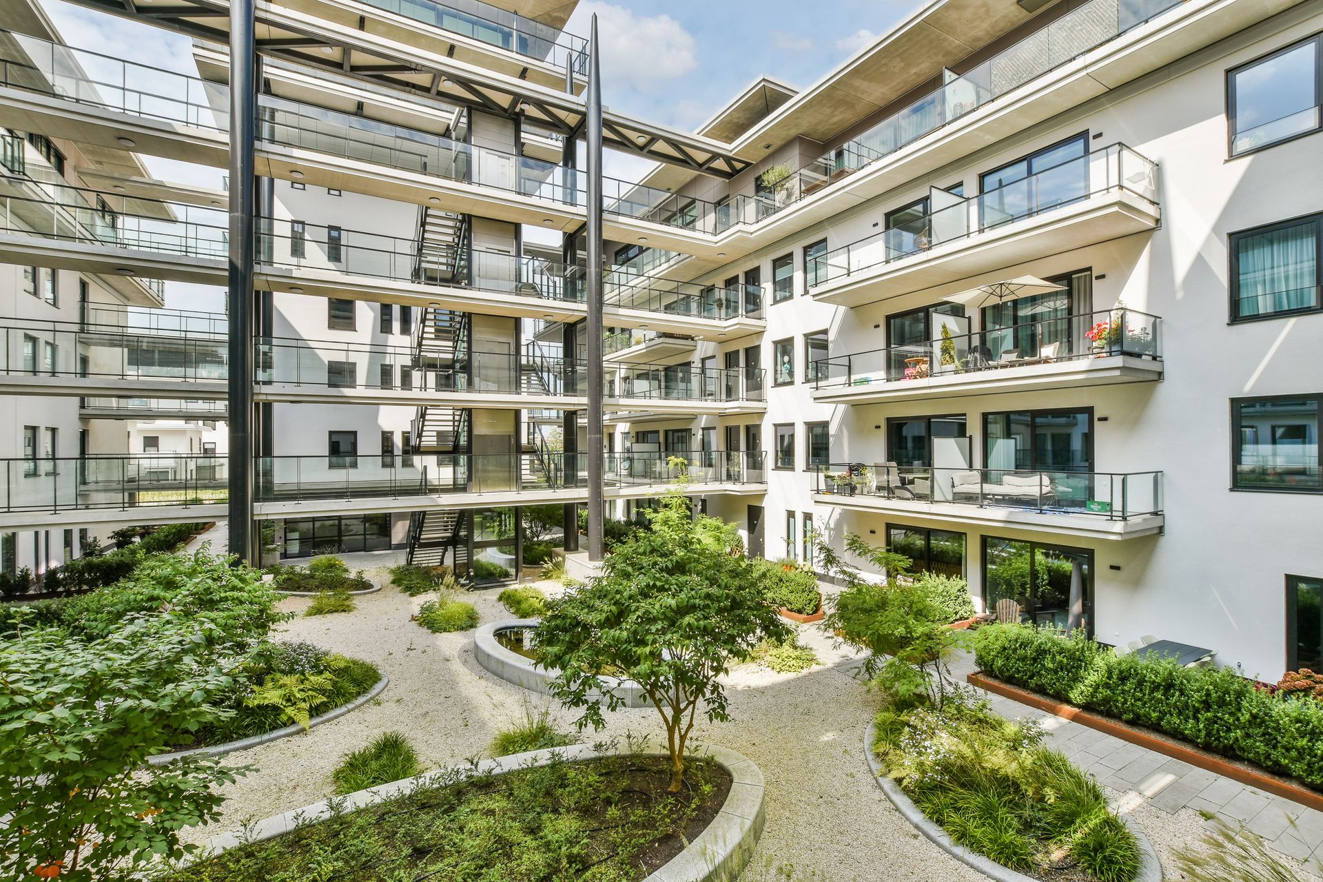 Modern apartment courtyard with balconies, glass railings, and landscaped paths