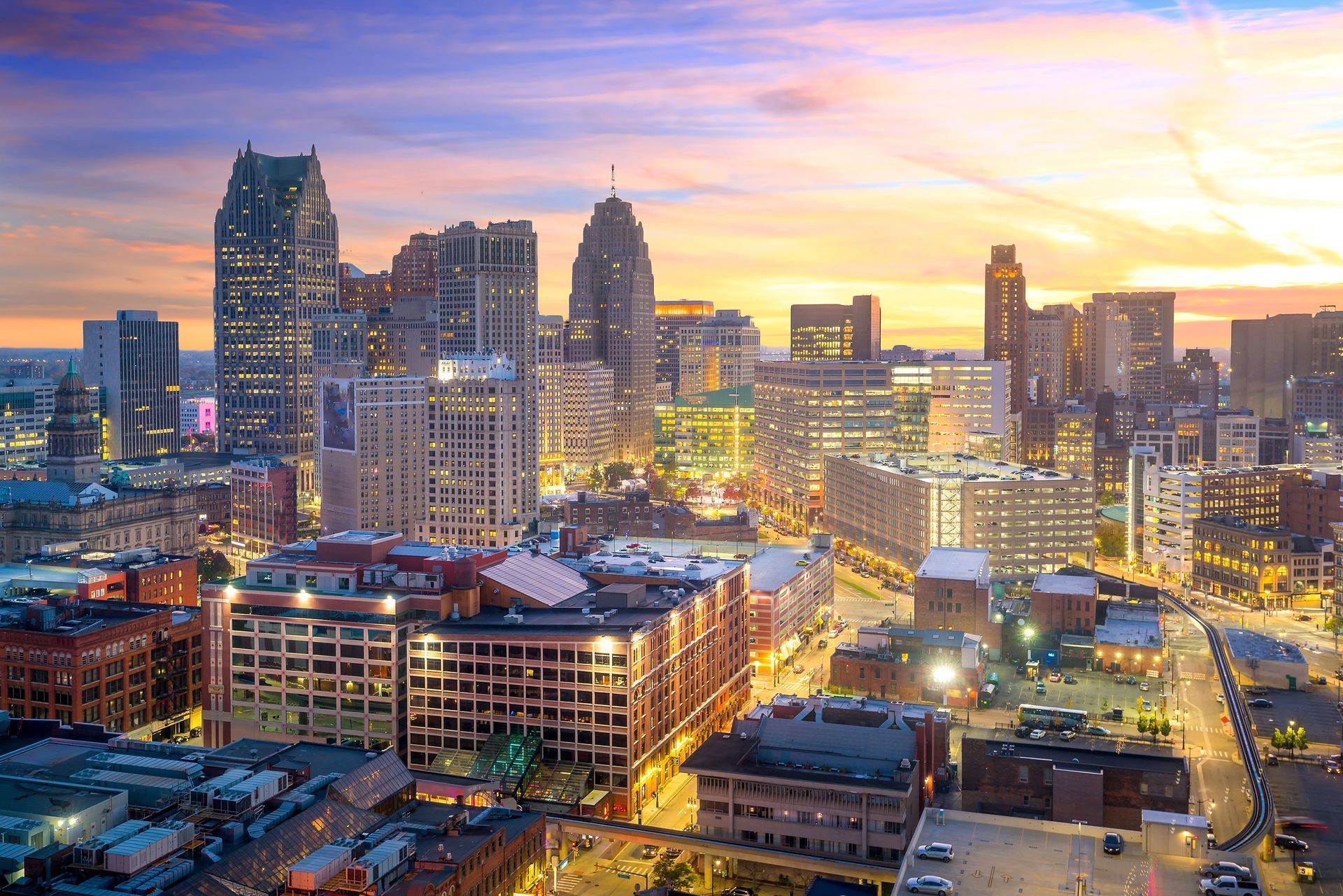 Sunset city skyline with tall buildings glowing over a busy downtown street grid