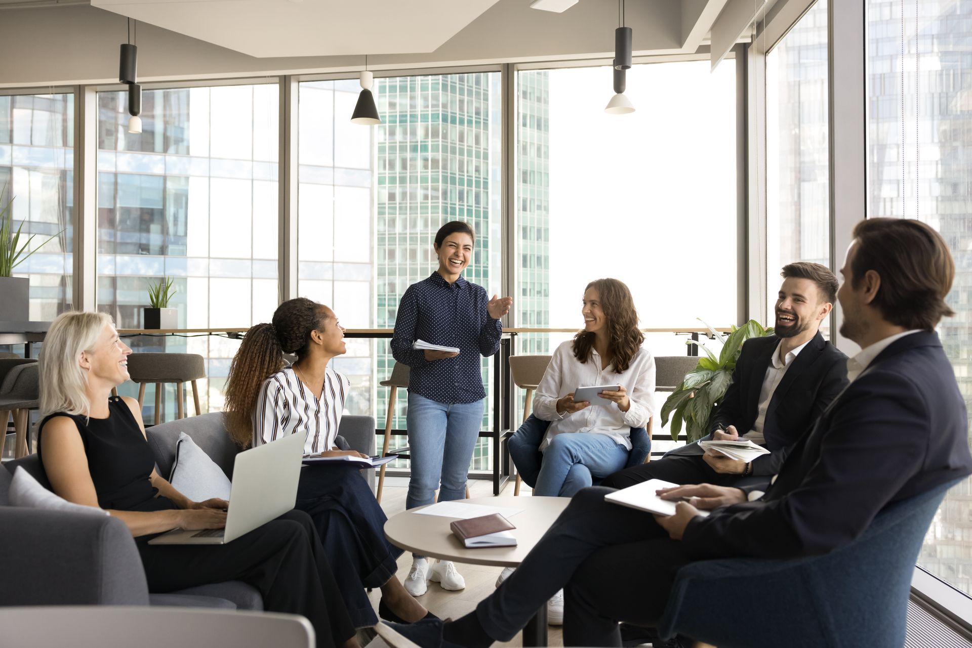 Group of professionals in business attire in a meeting, woman leading, natural light, large windows.