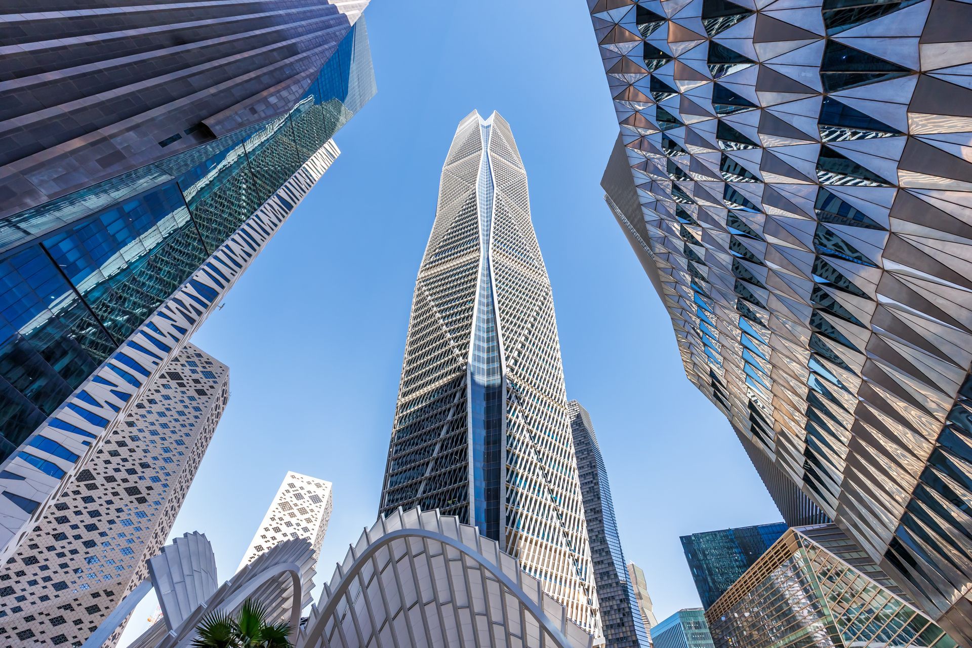 Looking up at modern glass skyscrapers against a blue sky in a city skyline