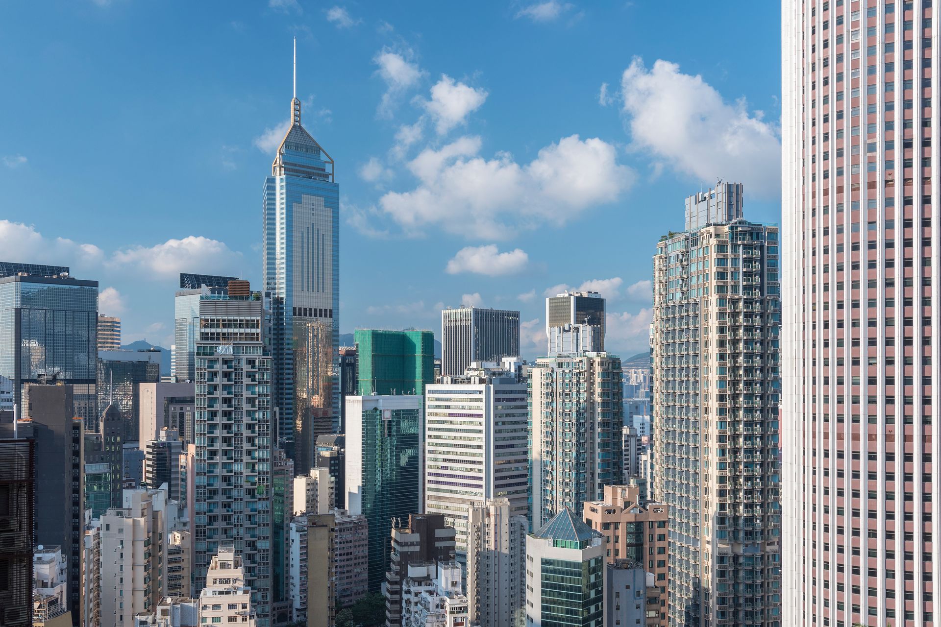Modern city skyline with tall glass skyscrapers under a blue sky with clouds