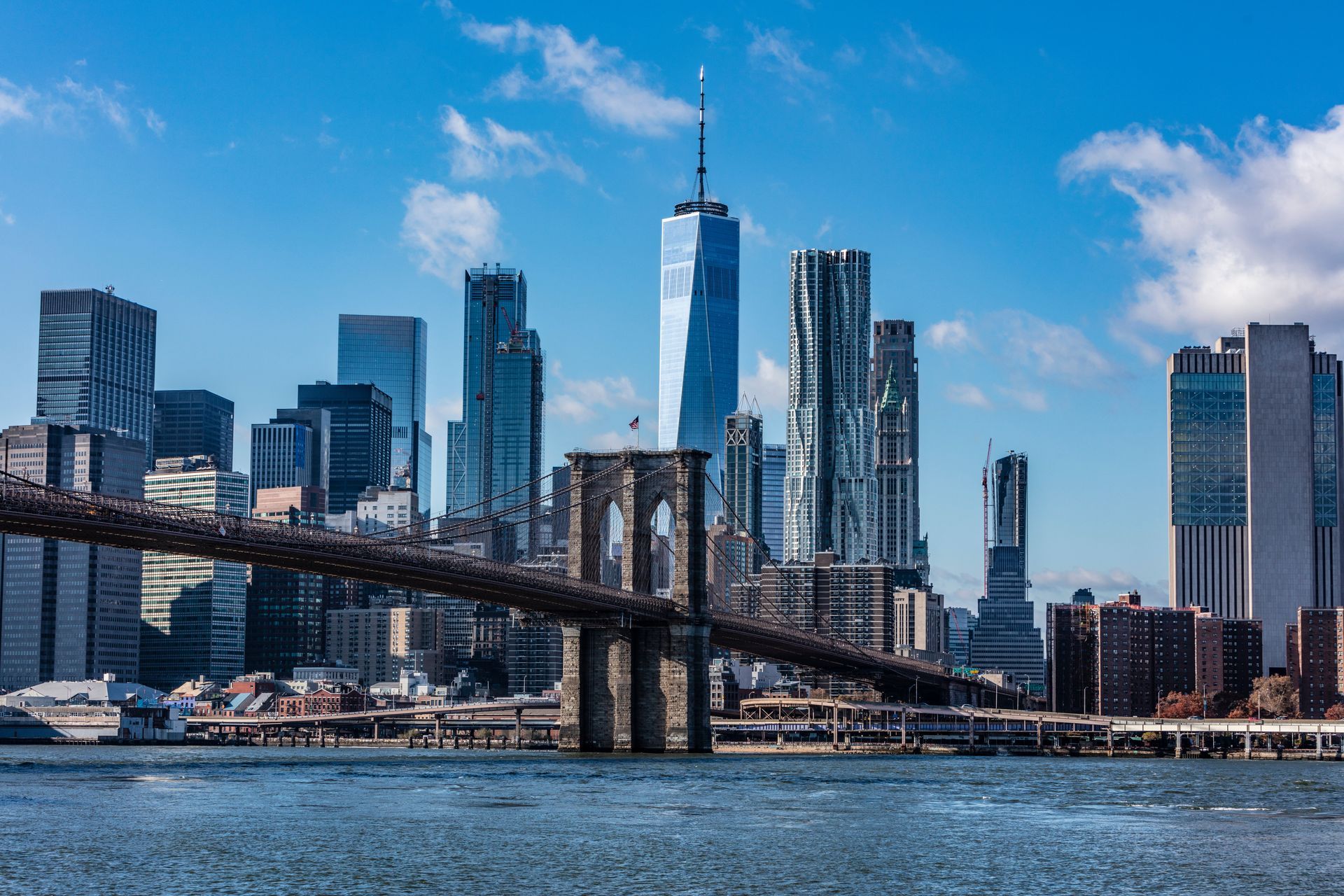 Brooklyn Bridge with Manhattan skyline and blue sky over the East River