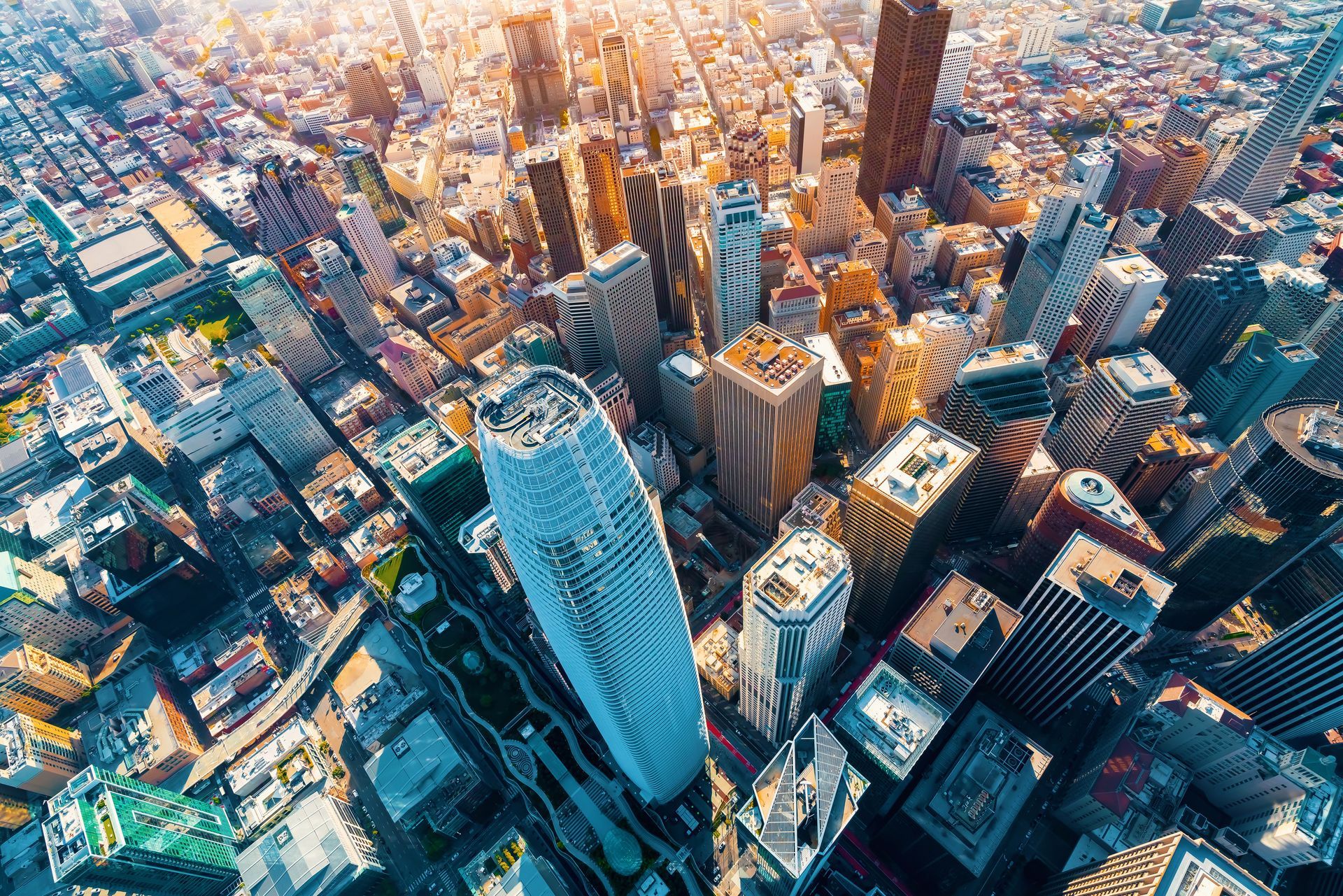 Aerial view of a city with many tall buildings, catching golden sunlight.
