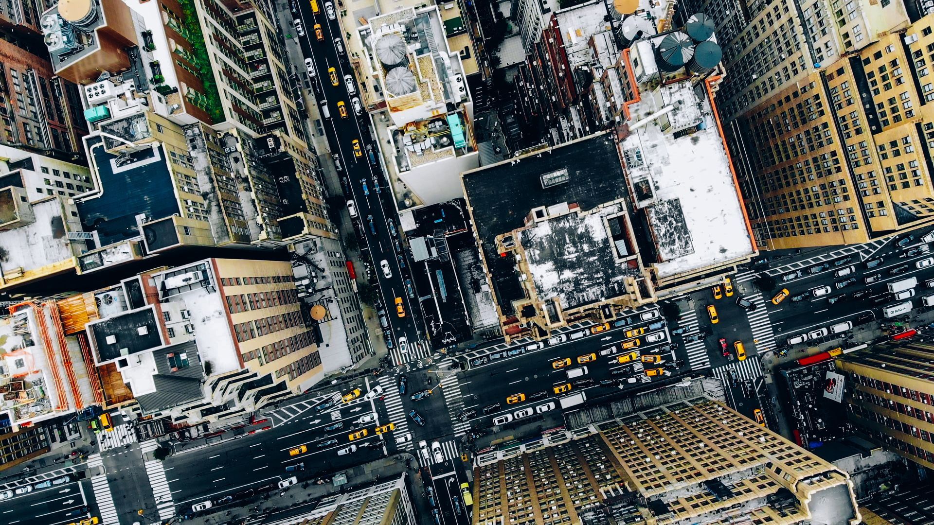 Aerial view of a busy city intersection with tall buildings and heavy traffic.