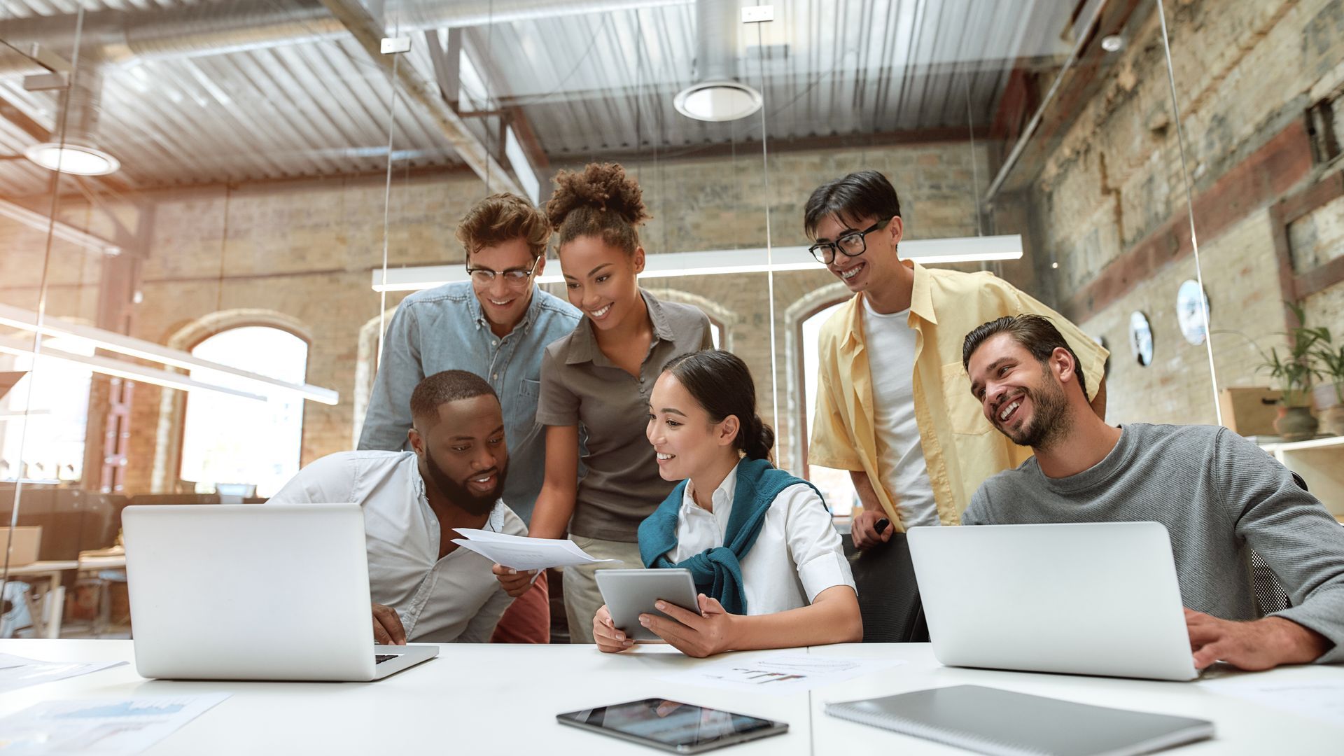 Colleagues collaborating around laptops in a bright office workspace
