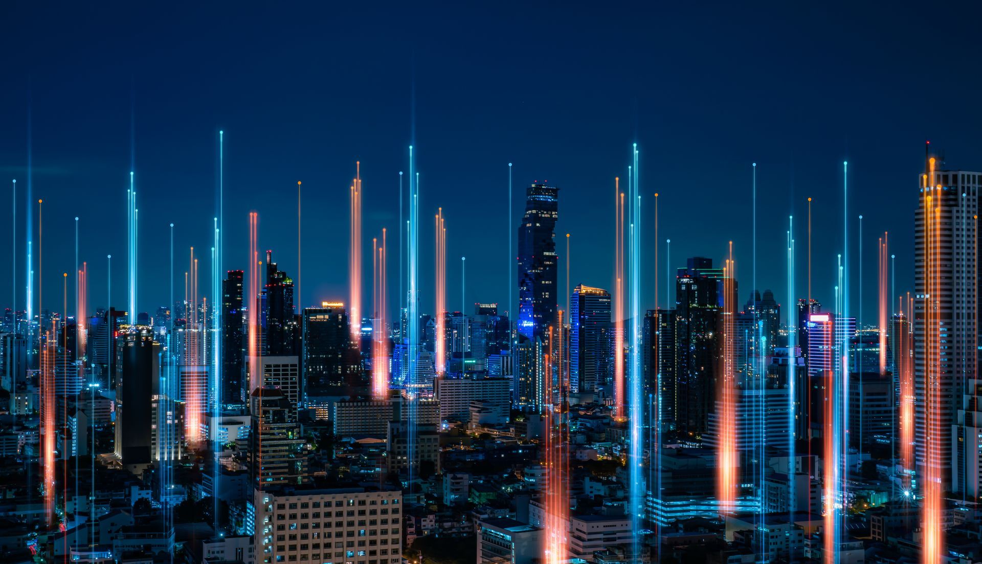 An aerial view of a city at night with a lot of lights coming out of the buildings.
