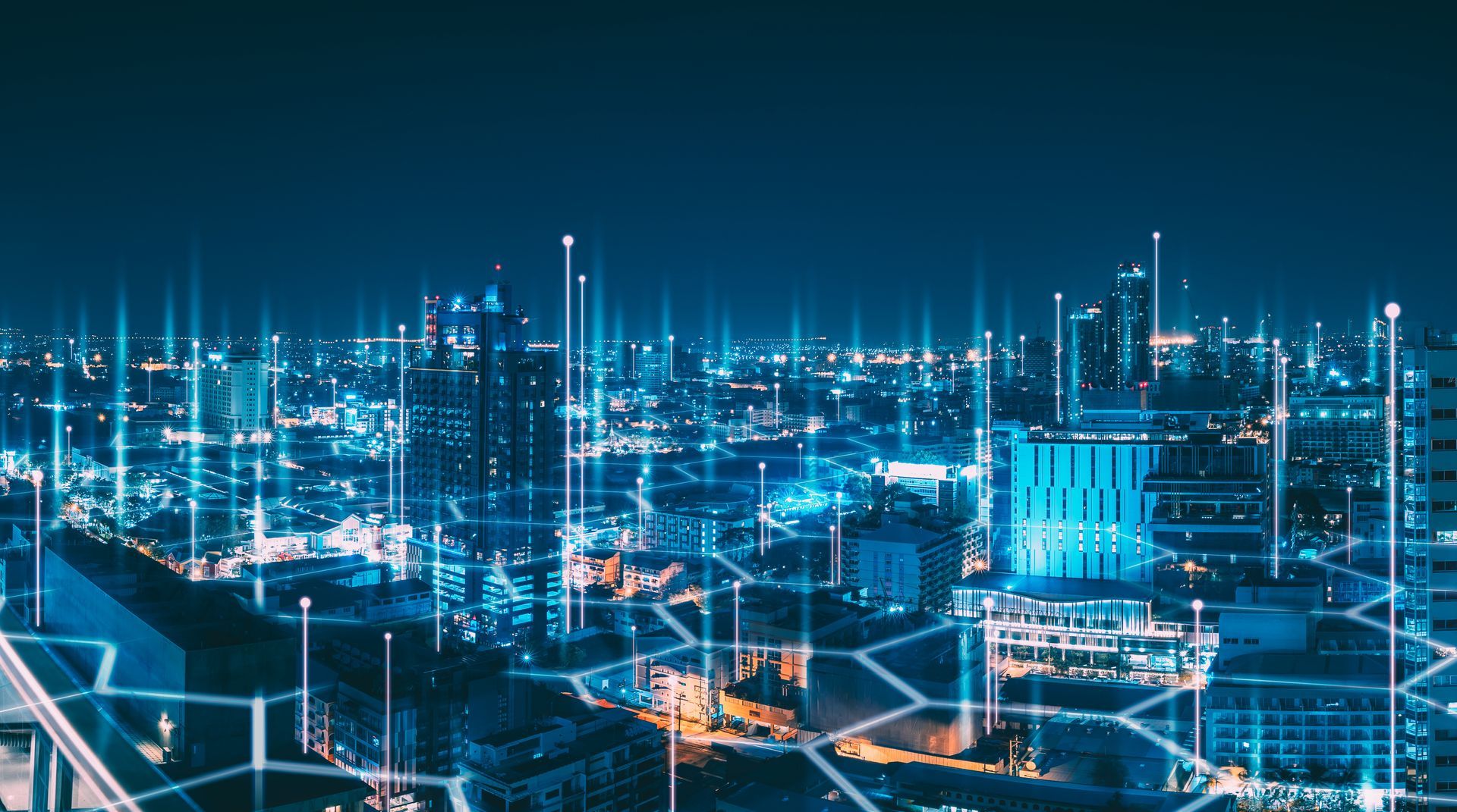 Cityscape at night with blue digital lines connecting buildings, representing data flow.