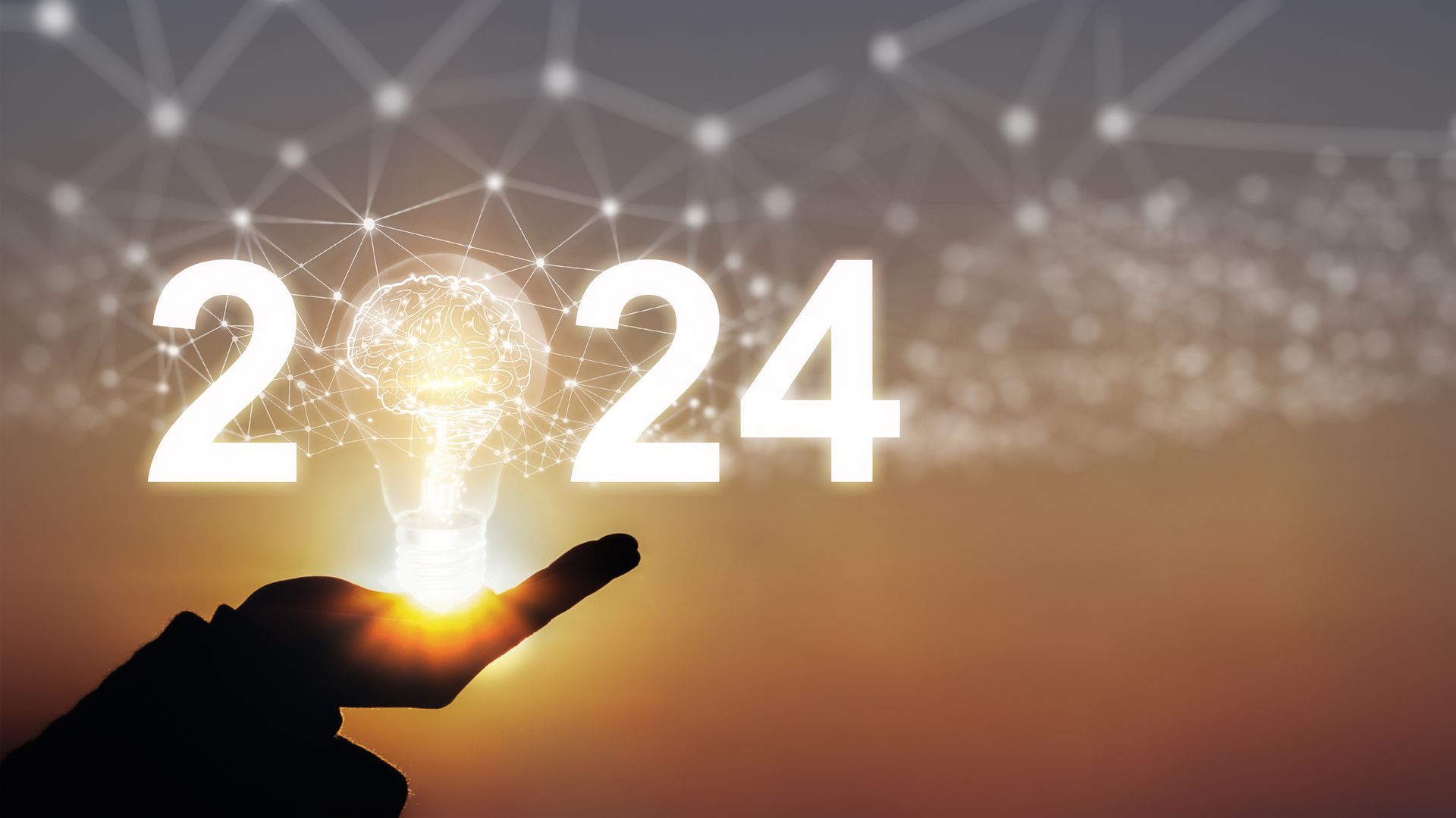 A hand is holding a light bulb in front of the number 2024.