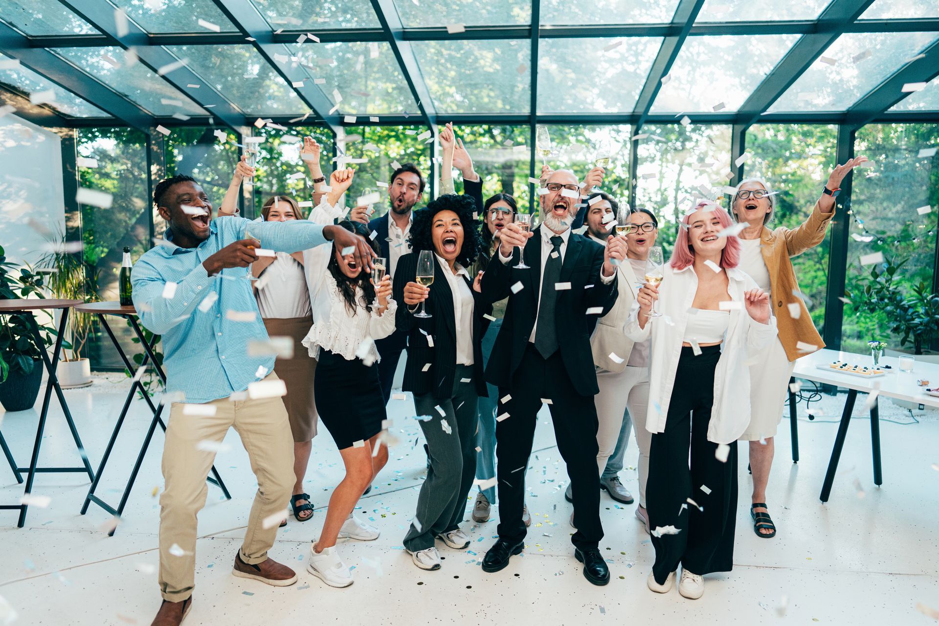 A group of people are standing in a room holding champagne glasses and confetti.