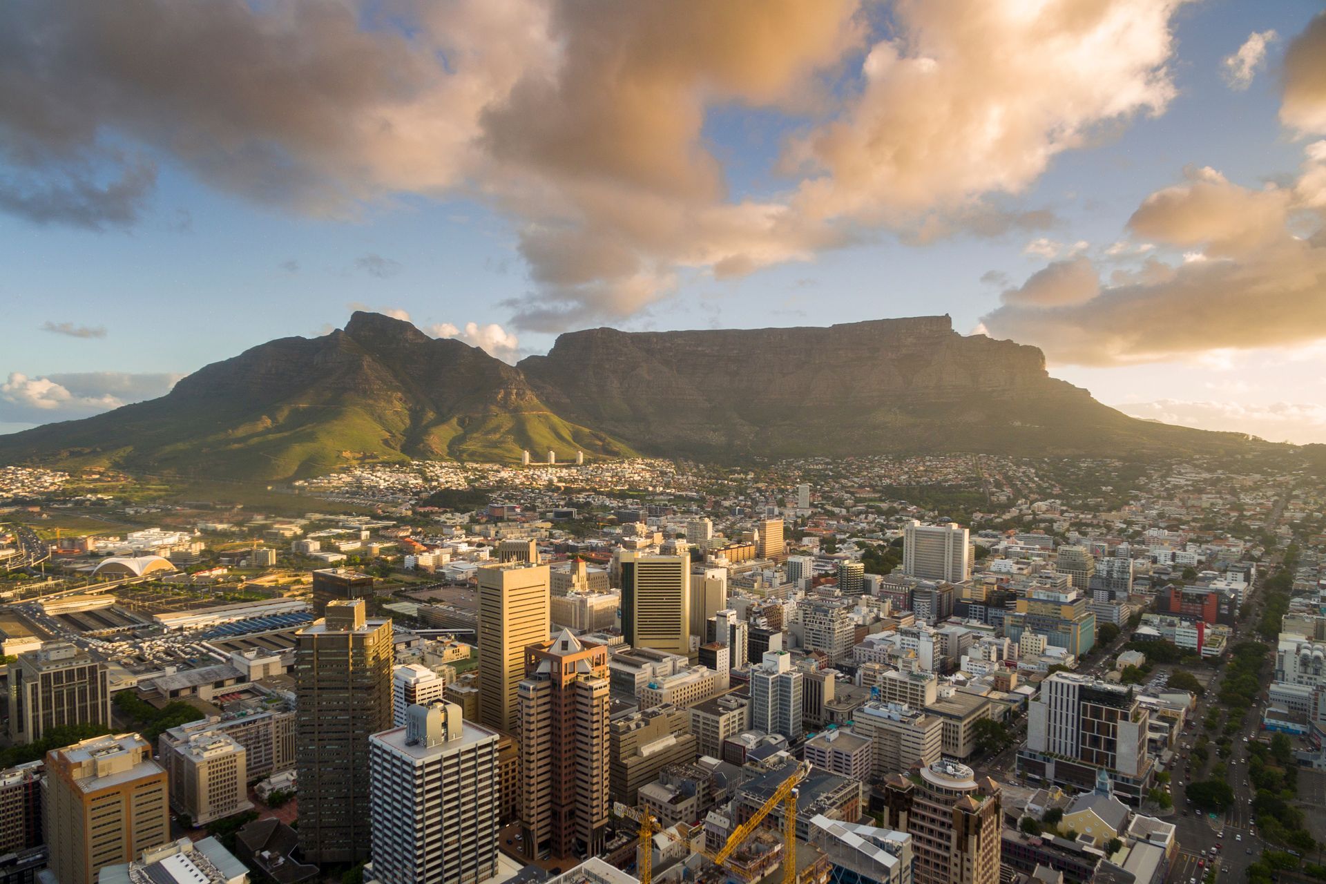 City skyline at sunset with Table Mountain and Lion's Head under dramatic clouds