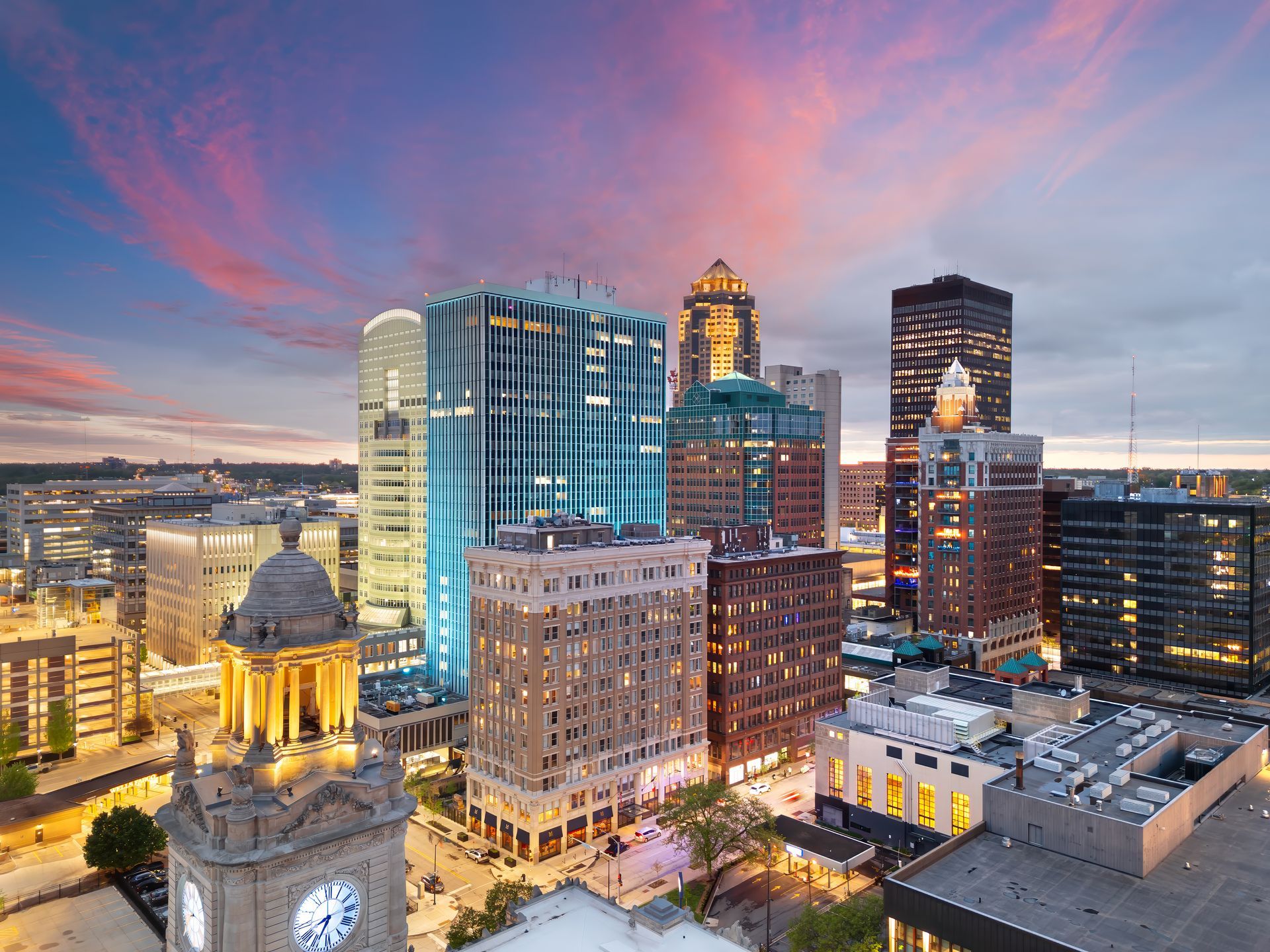 City skyline at sunset with illuminated skyscrapers and a pink-blue sky