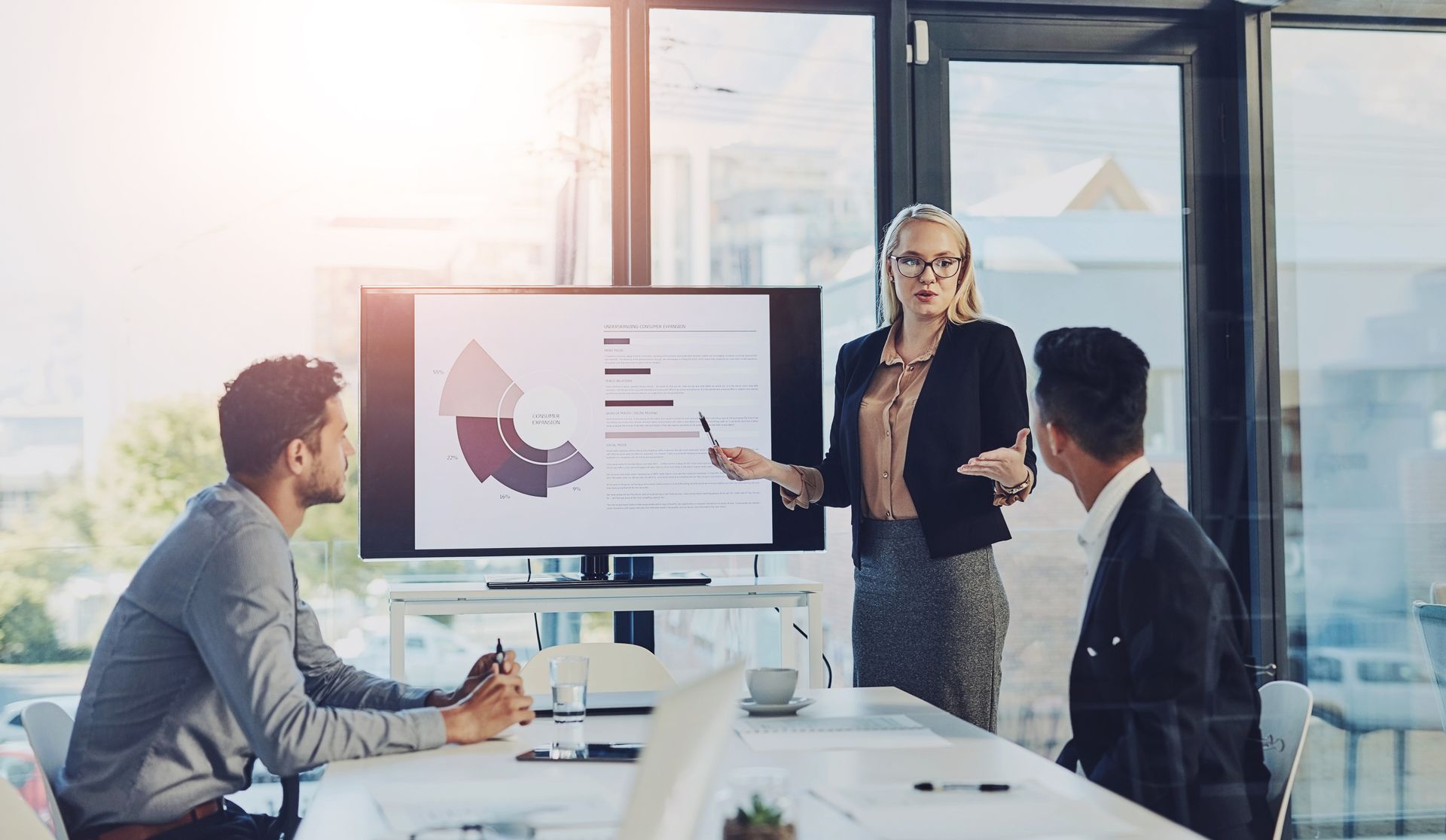 A woman is giving a presentation to a group of people in an office.