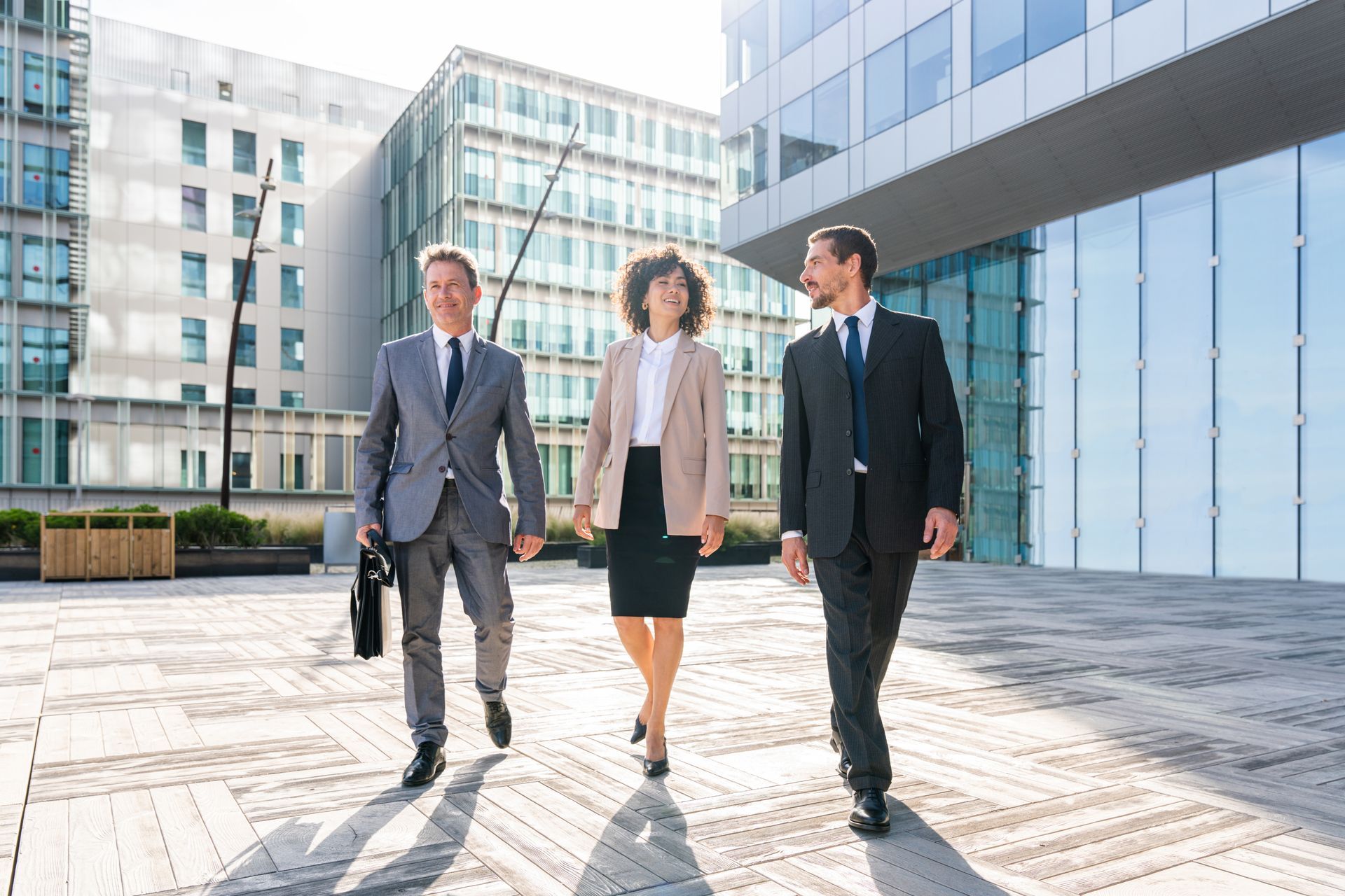Three business people walking outside a modern glass office building