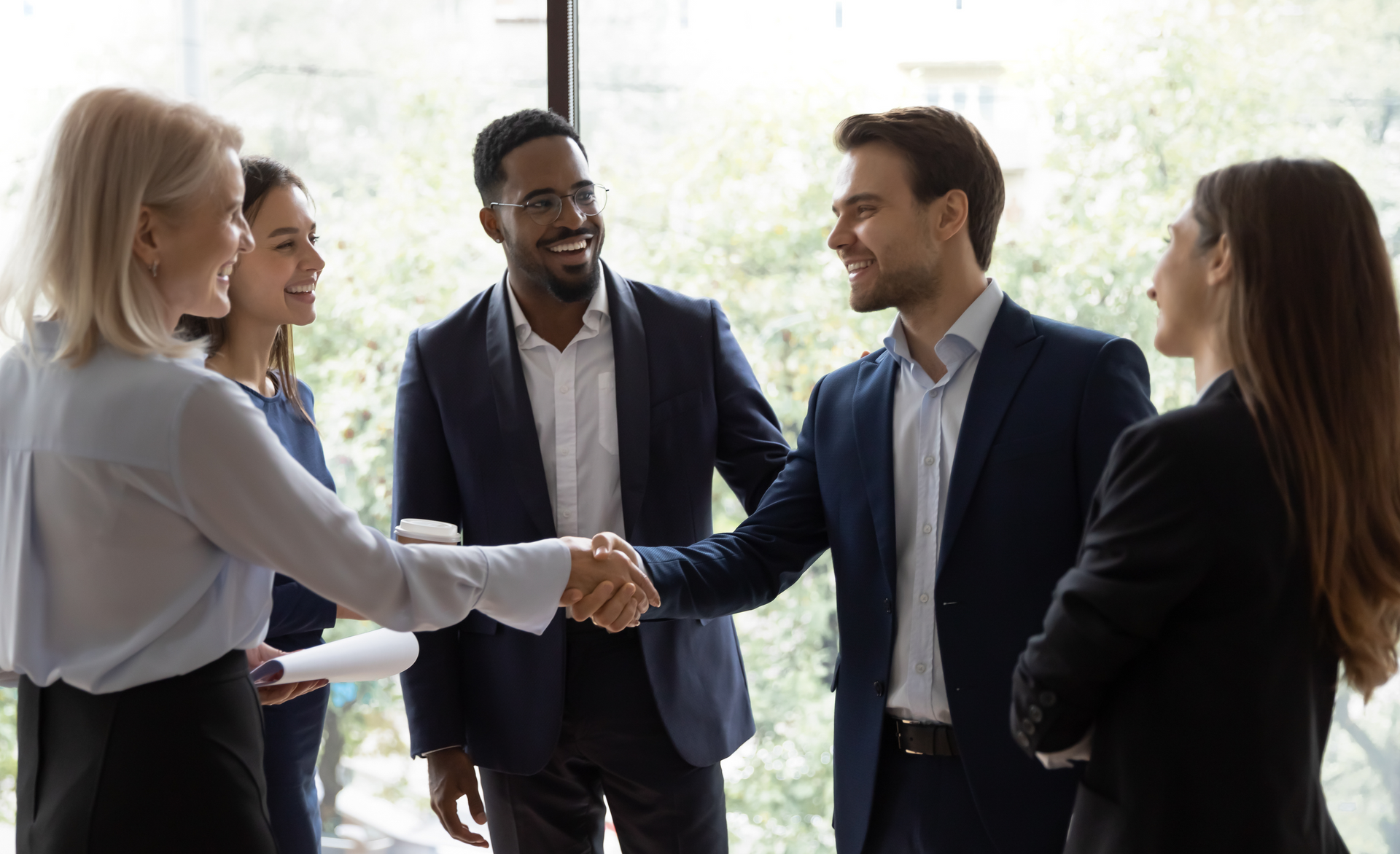 A group of business people are shaking hands in an office.
