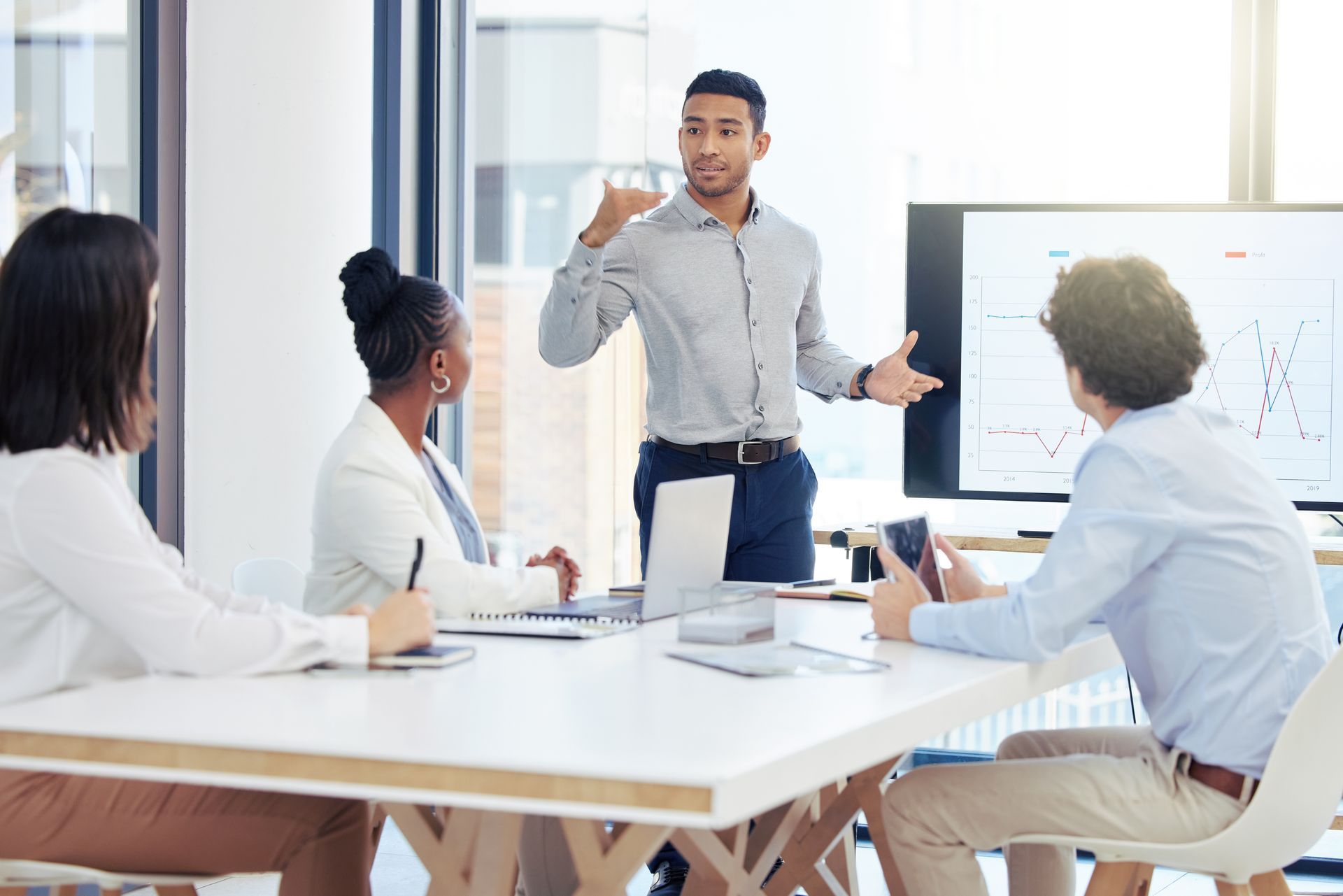 A man is giving a presentation to a group of people sitting around a table.