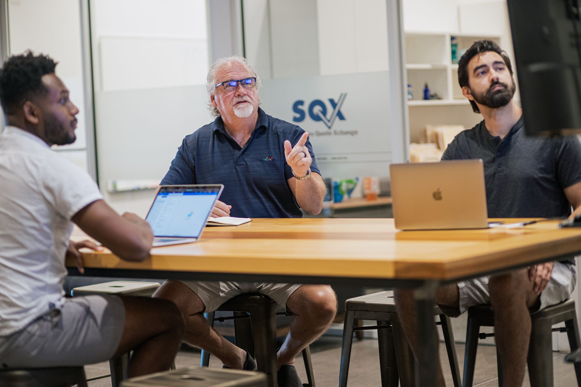 The SQX team is sitting at at table discussing their products.