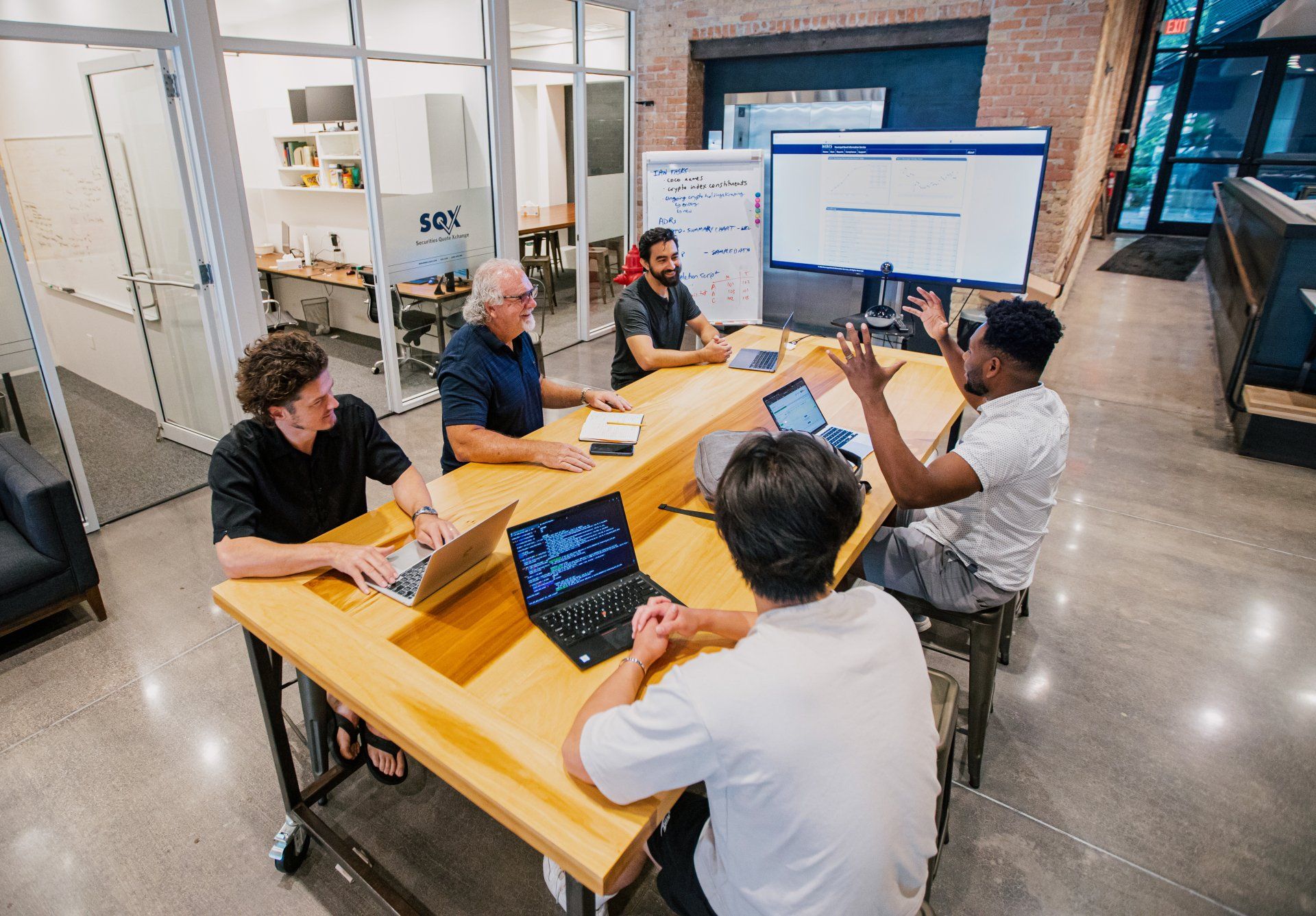 The SQX team meeting around a table.
