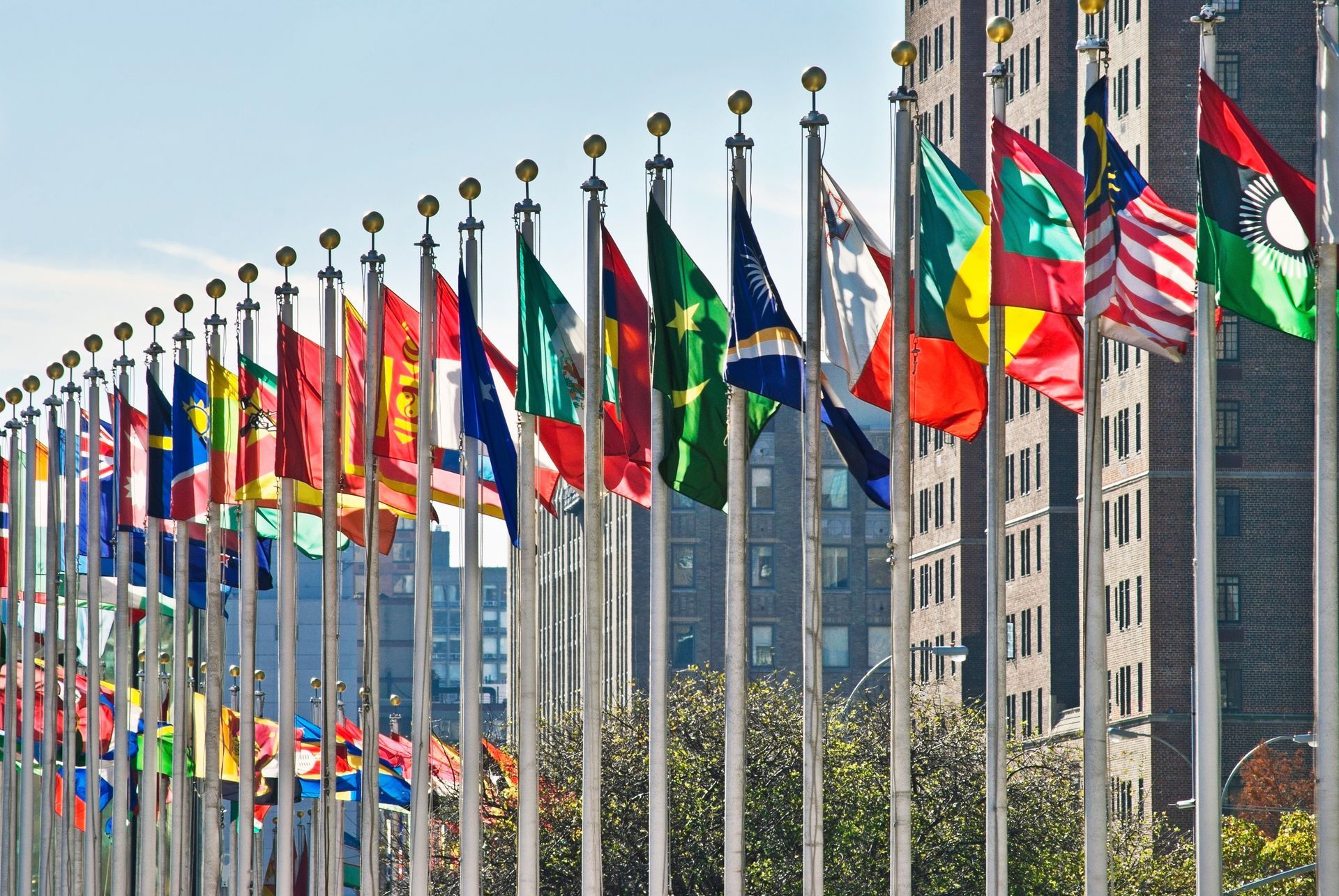 A row of flags flying in front of a building.