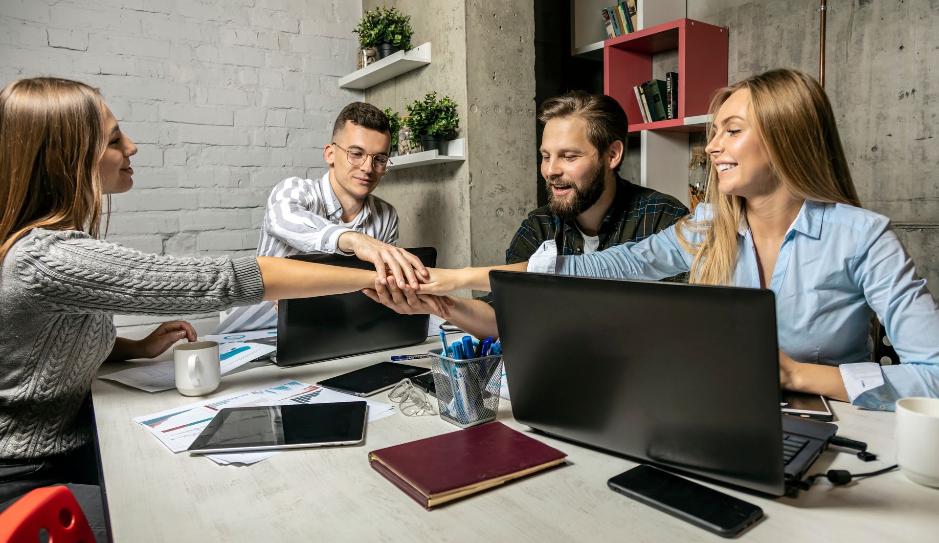 A group of people are putting their hands together in an office.