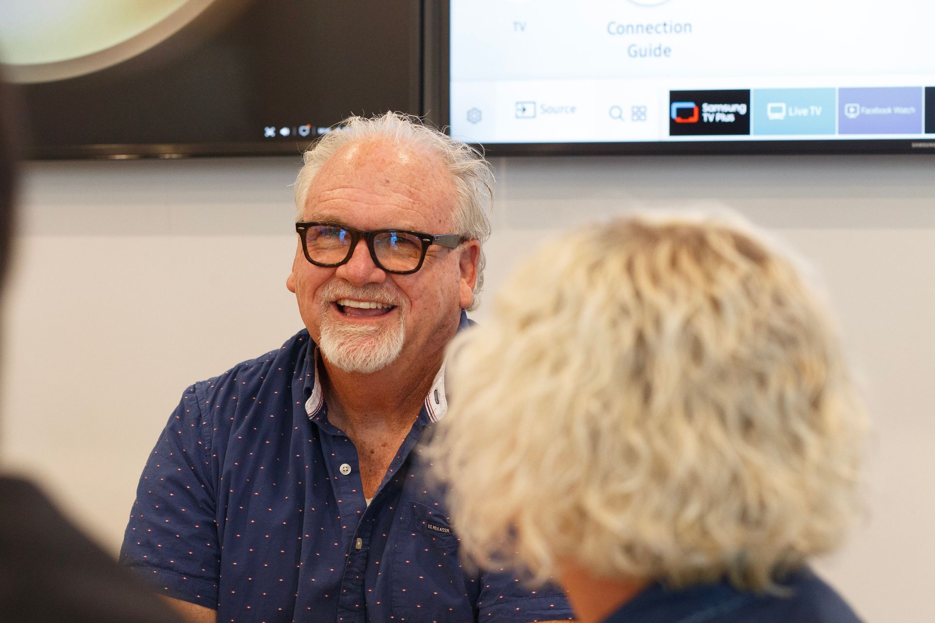 A man with glasses is smiling while sitting next to a woman.